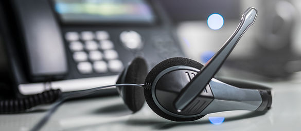 A telemarketing headset on a desk in front of a telephone handset.